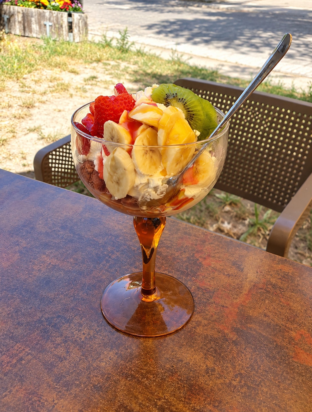 A fruit cup of strawberries, banana and kiwi in an amber glass on the terrace