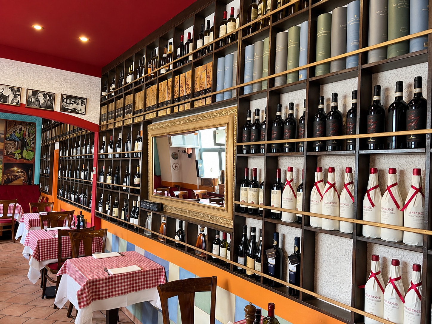 Dining room with the wine wall, a gilt-framed mirror and checked tablecloths