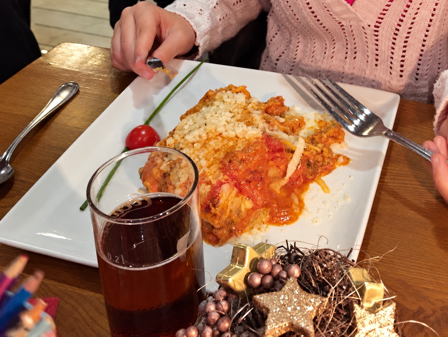 Baked lasagne with tomato sauce on a square plate beside festive decorations