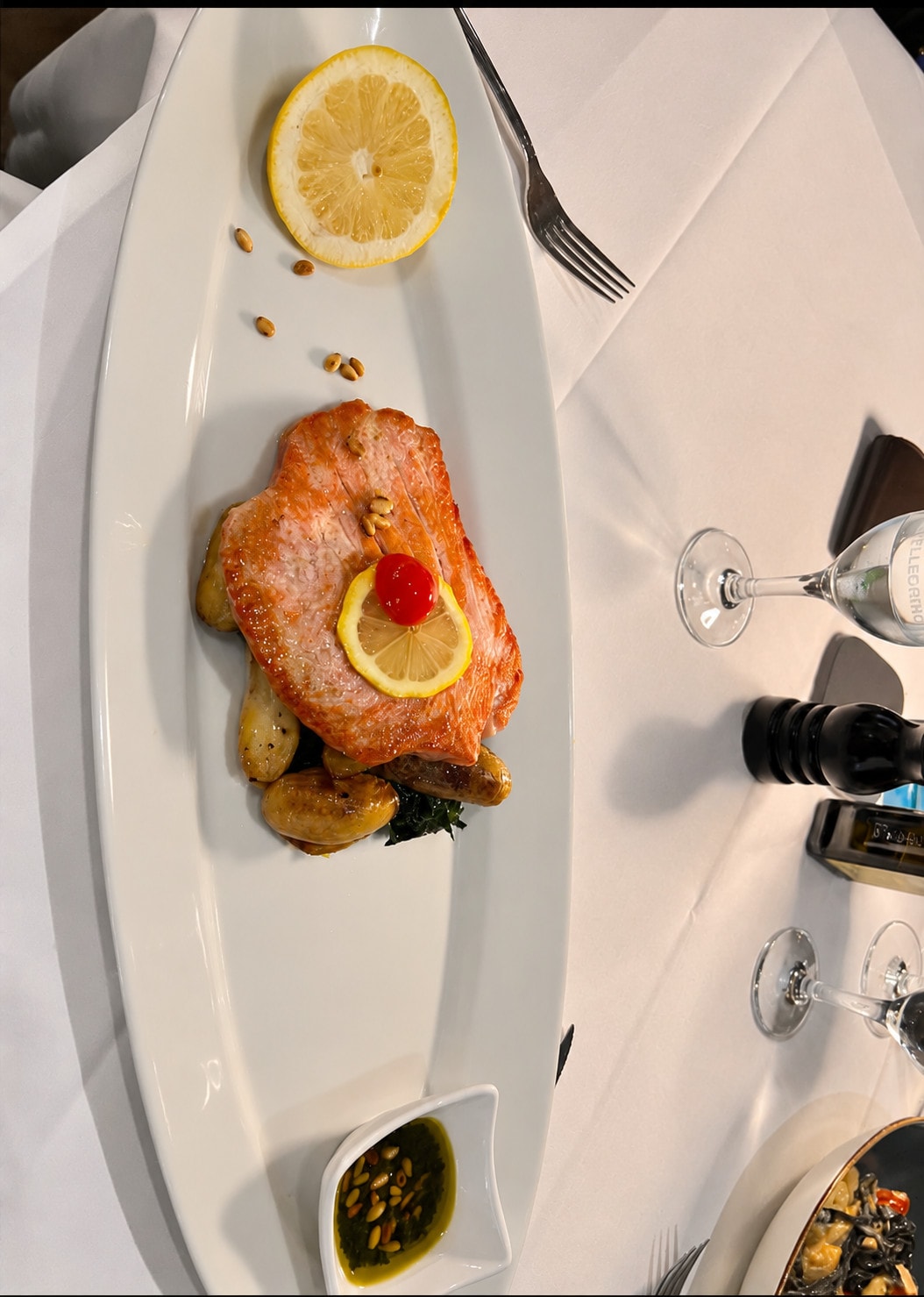 Grilled salmon fillet with lemon and potatoes on a long white platter