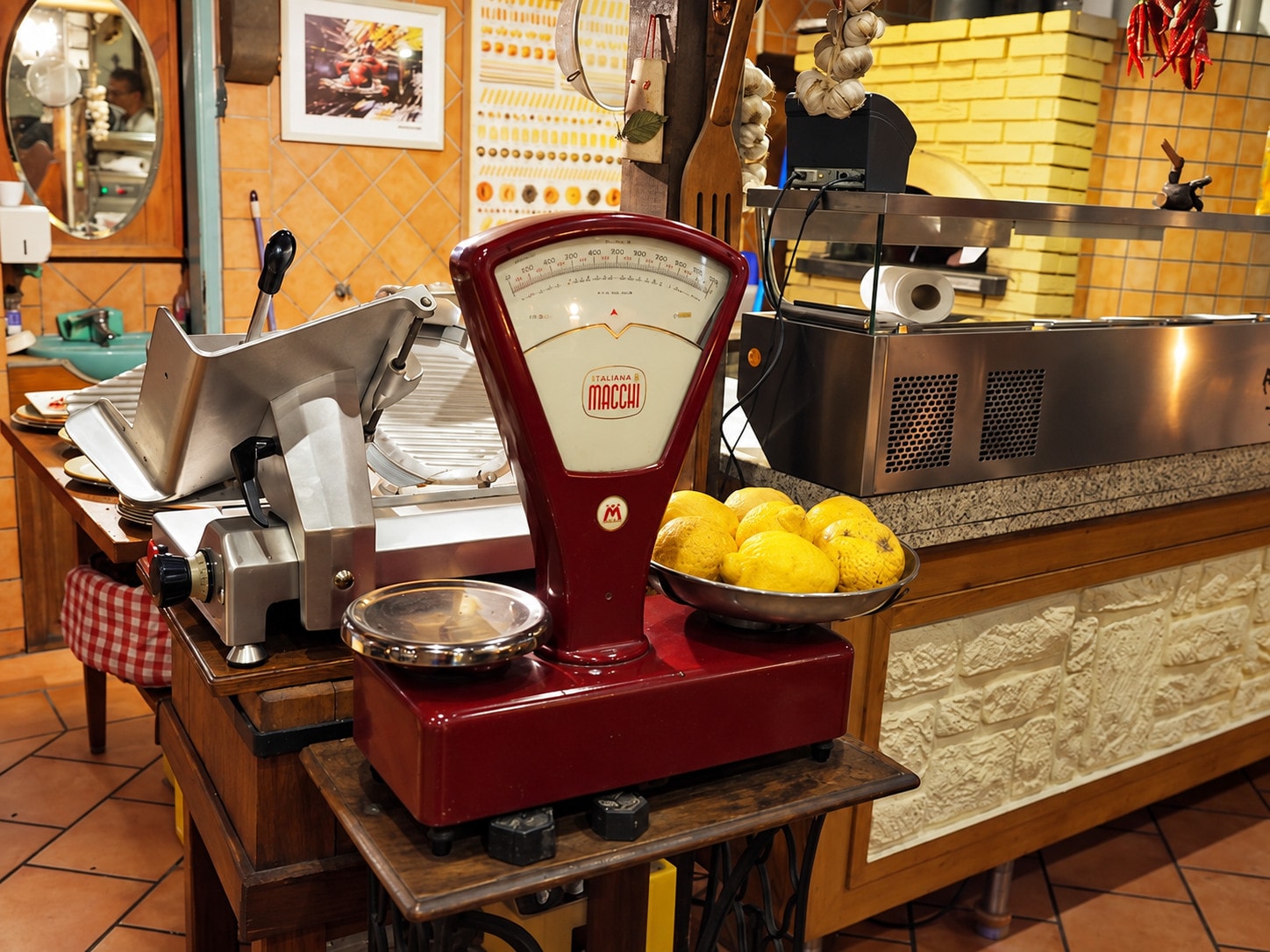 A vintage red scale and a meat slicer beside a bowl of lemons