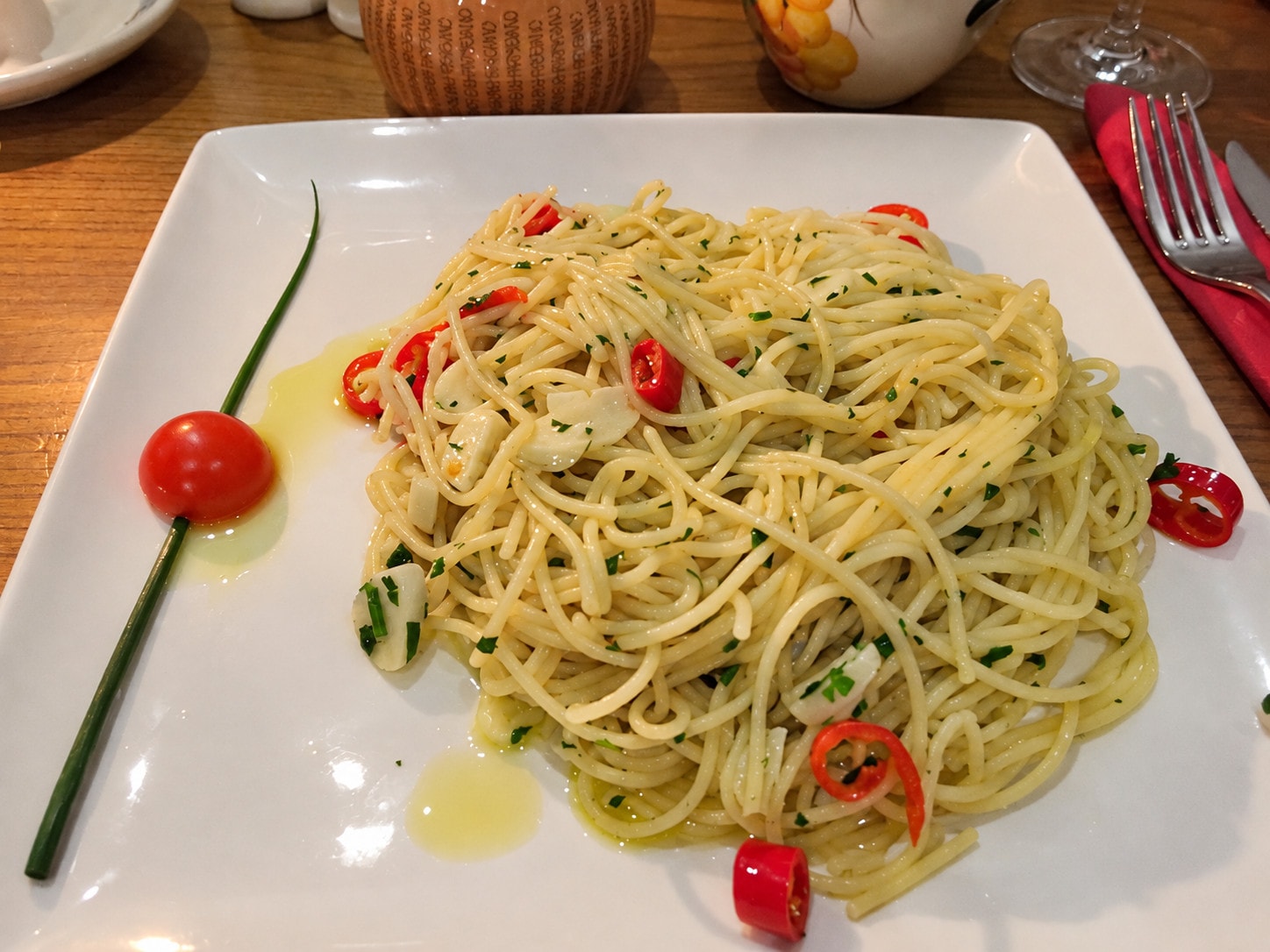 Spaghetti aglio, olio e peperoncino with red chillies on a square plate
