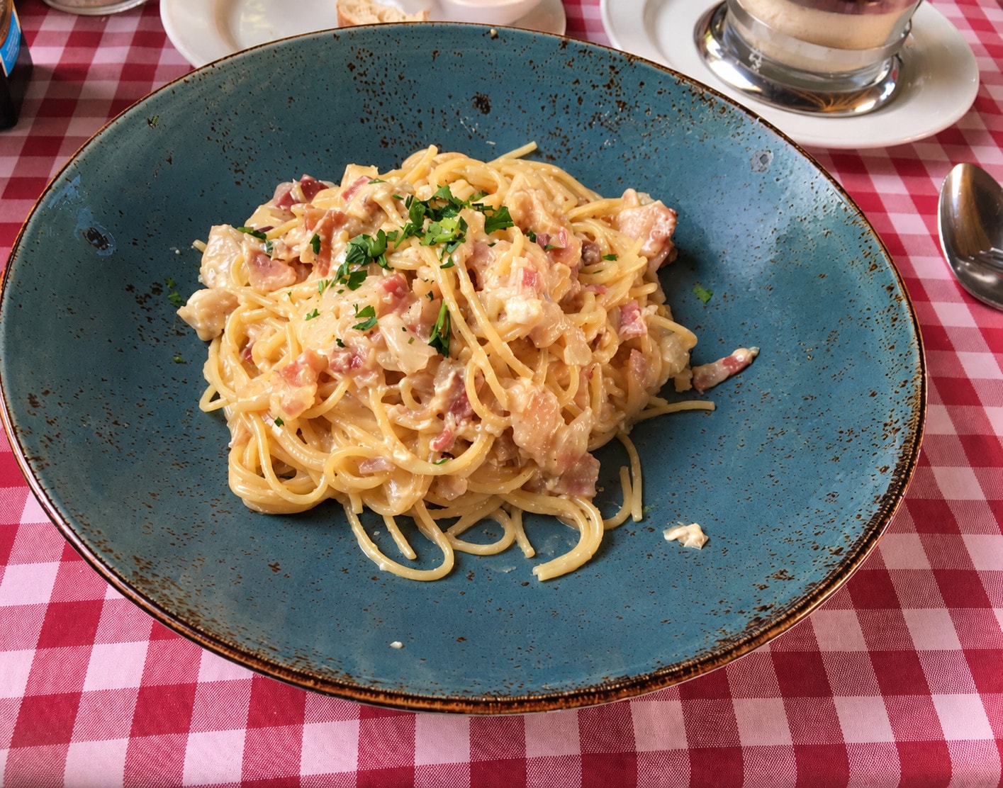 Spaghetti carbonara with bacon and parsley on a blue plate