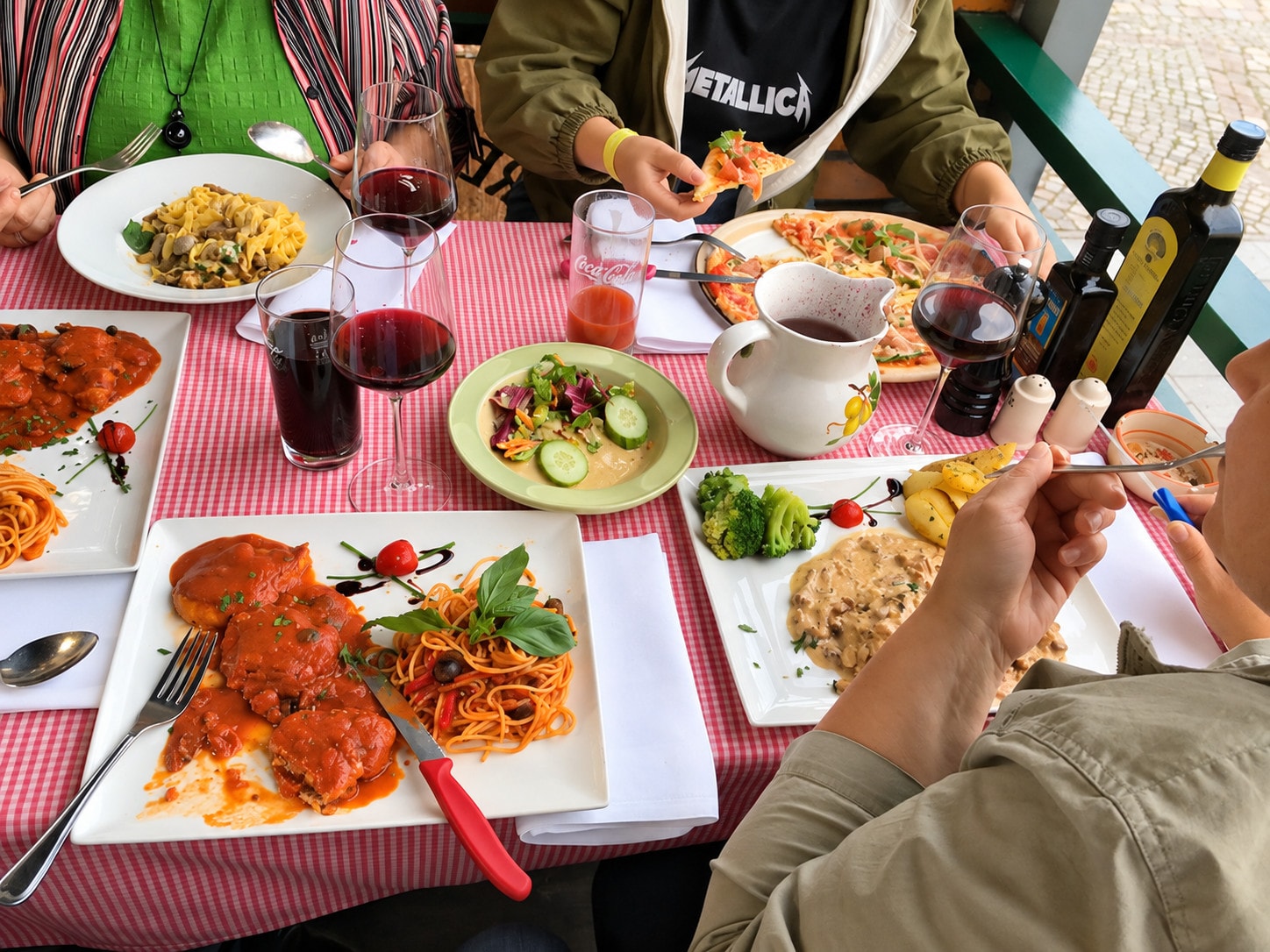 Guests at a generous table with pasta, scaloppine, salad and red wine