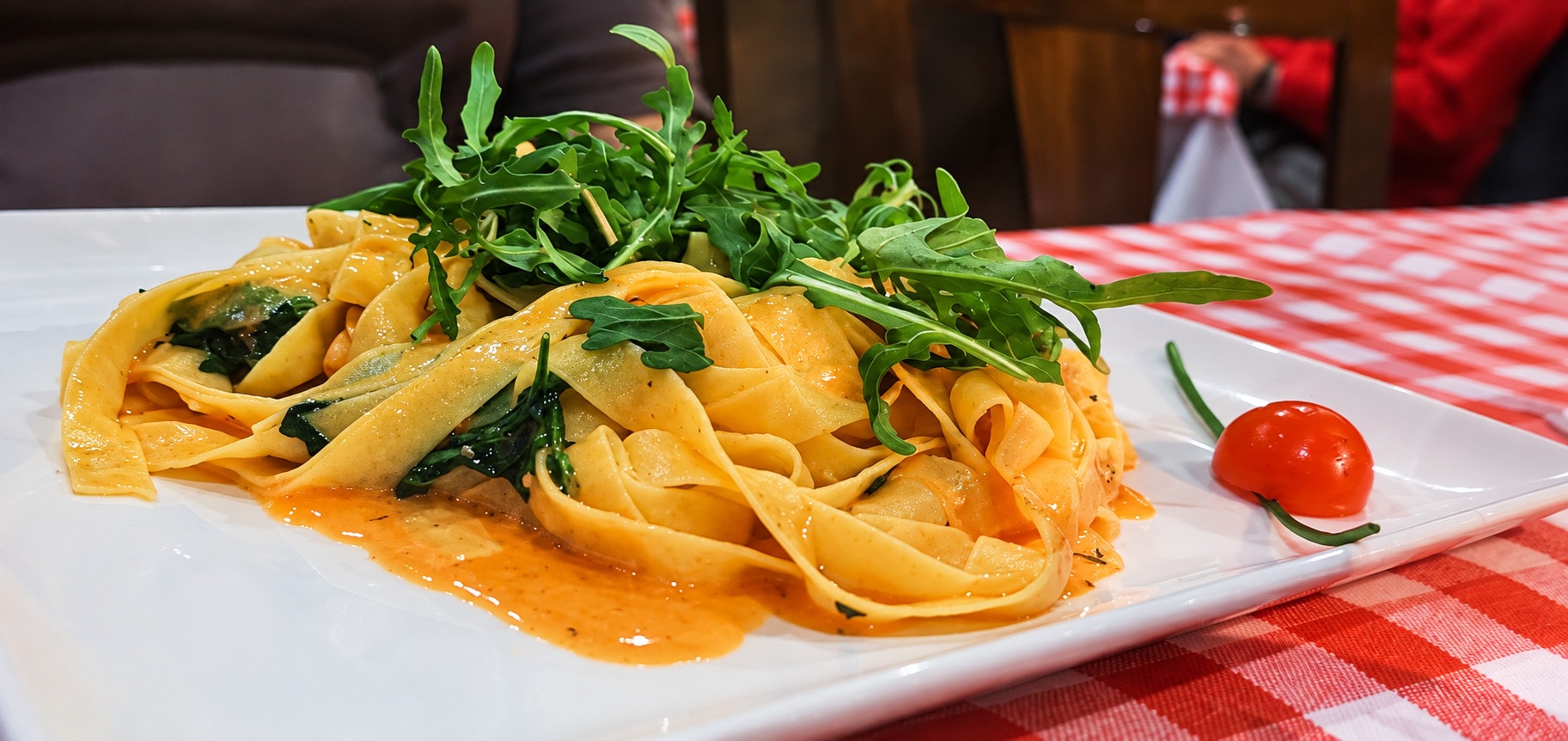 Homemade tagliatelle in tomato sauce topped with fresh rocket