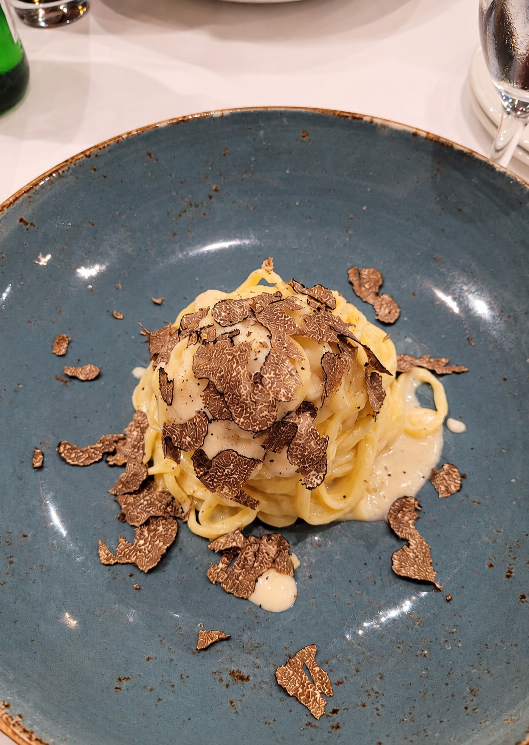 Tagliolini in a cream sauce with freshly shaved truffle on a blue plate