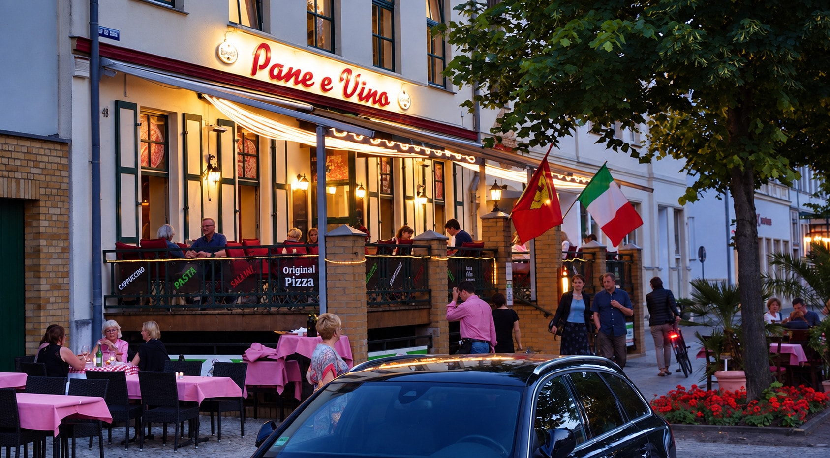 The busy Pane e Vino terrace in the evening with Italian flags and string lights