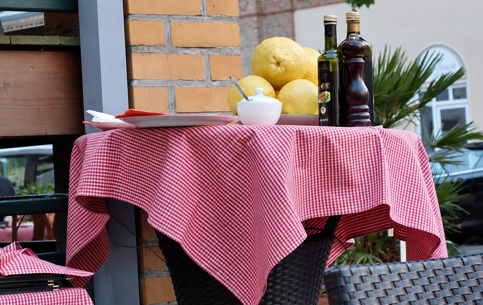 A checked high table on the terrace with lemons, olive oil and a pepper mill