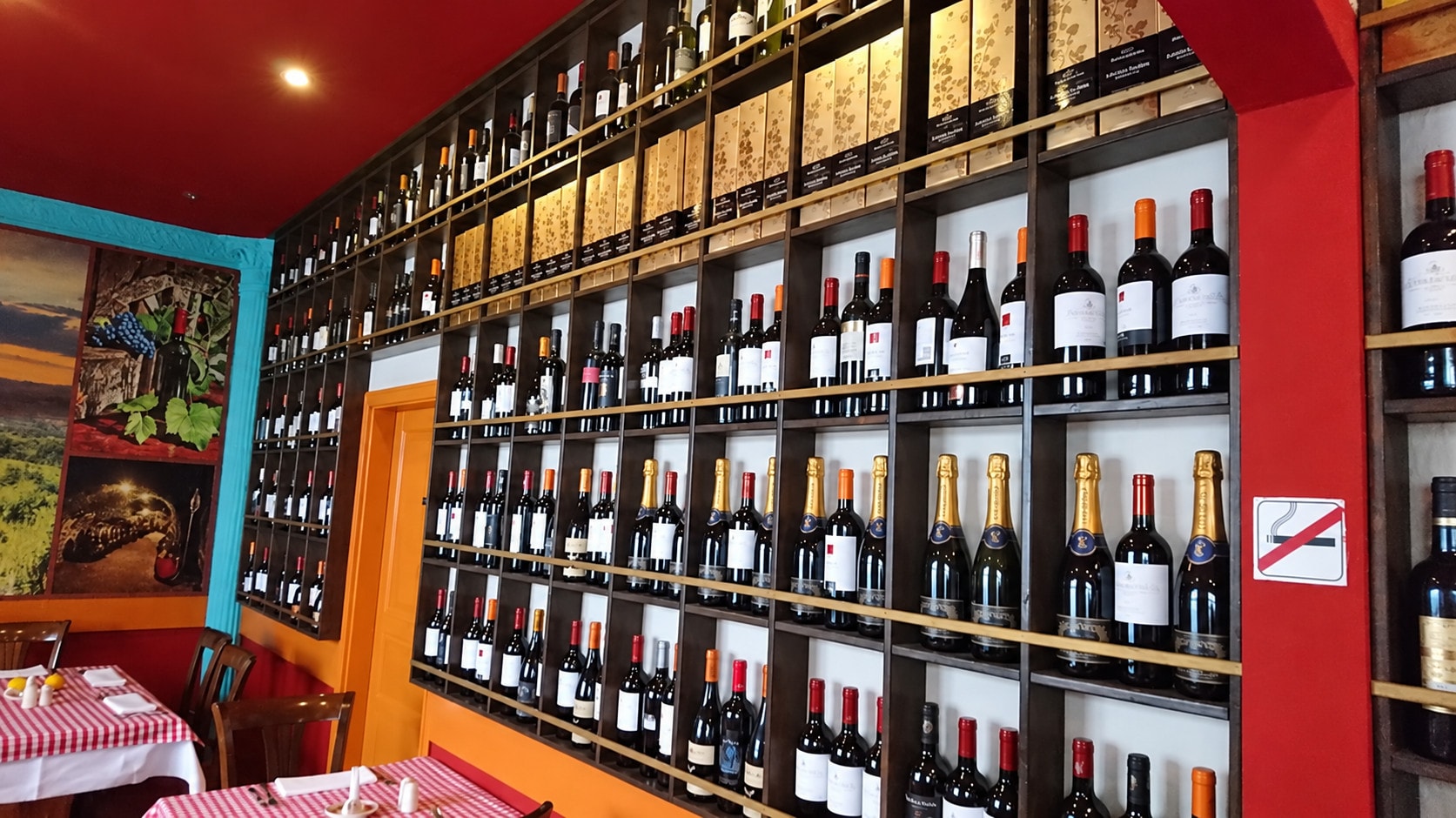 The red wine wall with hundreds of bottles and set tables in the background
