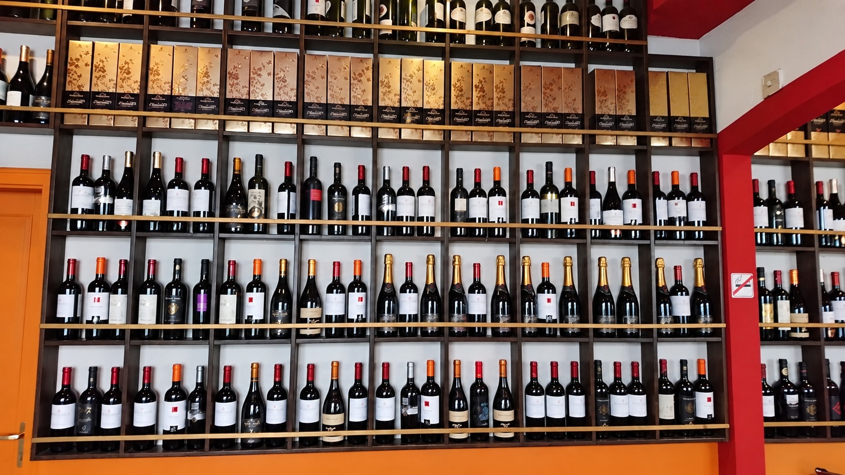 Front view of the wine shelves lined with red wine and prosecco